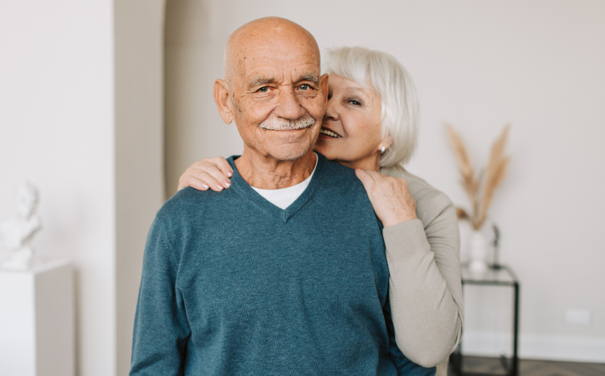 An elderly couple embracing warmly, smiling happily